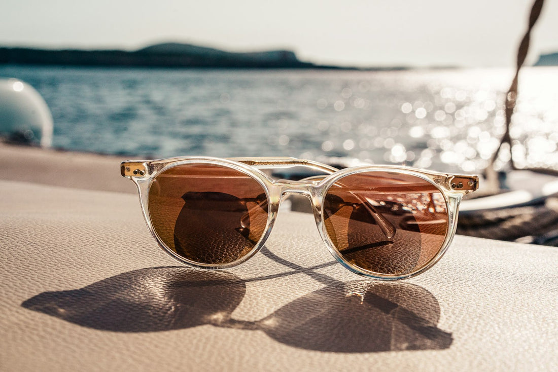 Designer sunglasses on water with island view - guide to choosing frames for face shape